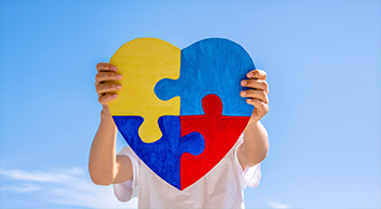 puzzle w kształcie serca, które trzyma dziecko na tle nieba
