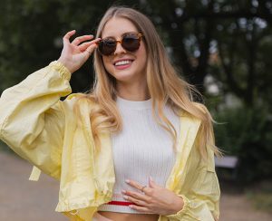 kobieta w krótkiej kurtce w kolorze limonkowym i przeciwsłonecznych okularach