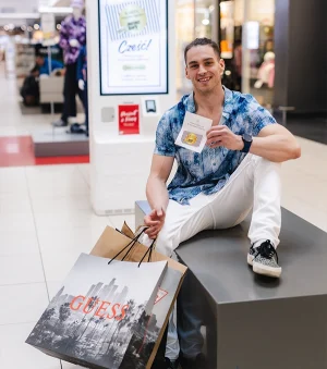 mężczyzna siedzący w outlet park szczecin z zakupami i kartą podarunkową