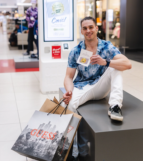mężczyzna siedzący w outlet park szczecin z zakupami i kartą podarunkową